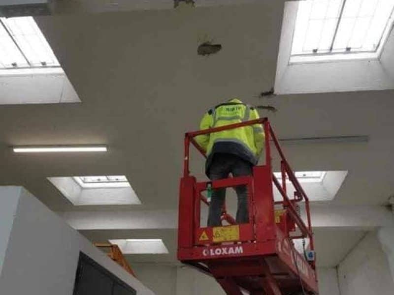 Ingénieur BIBTP inspectant la sous-face d'un plancher de locaux tertiaires depuis une nacelle