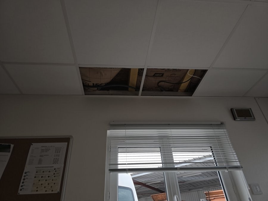 Dalles de faux plafond déposées révélant les solives bois du plancher de la mezzanine